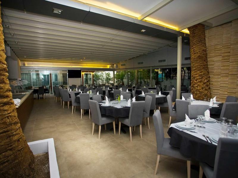 Modernes, helles Restaurant mit grauen Stühlen, gedeckten Tischen und großen Fensterfronten.