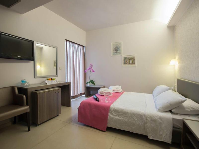 Ein helles, modern eingerichtetes Hotelzimmer mit Doppelbett, Schreibtisch und Fernseher.