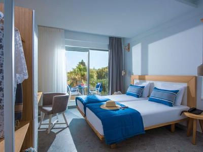 Moderne hotelkamer met tweepersoonsbed, blauw-witte beddengoed en uitzicht op het zwembad.