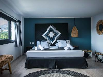 Camera moderna con letto grande, parete scura e pavimento in legno chiaro