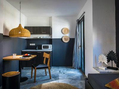 Camera d'hotel moderna con mobili scuri, tavolo da pranzo e elementi decorativi sulla parete.