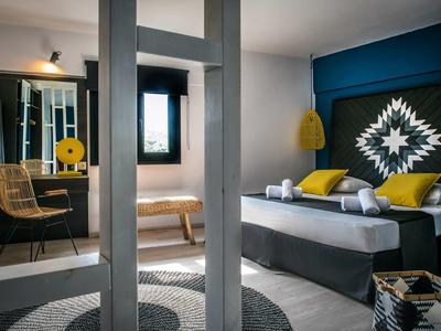 Camera d'hotel moderna con parete blu, letto matrimoniale, sedia e scrivania con specchio.