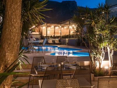 Piscina esterna illuminata e area salotto di un hotel in serata.