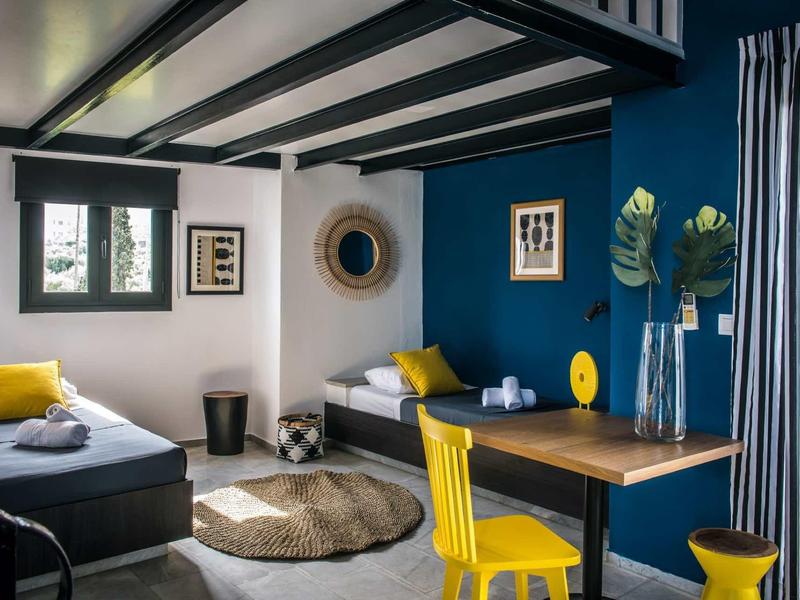 Accogliente zona giorno con parete blu, sedie gialle e mobili moderni.