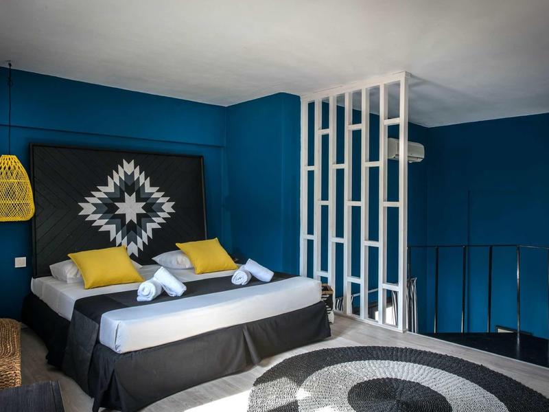 Camera da letto moderna con pareti blu, letto matrimoniale e cuscini decorativi.