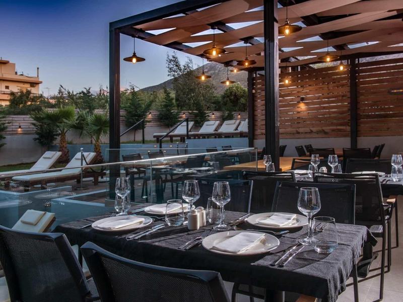 Ristorante elegante all'aperto con tavoli apparecchiati e poltrone lounge al crepuscolo.