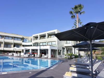 Zona piscina moderna dell'hotel con sdraio e ombrelloni sotto un cielo sereno.