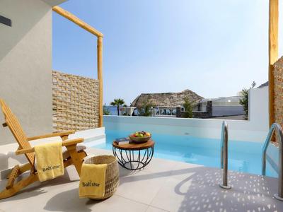 Vista di una piscina privata con sedia a sdraio e cesta di frutta sotto un cielo soleggiato.