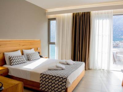 Hell und modern eingerichtetes Schlafzimmer mit großem Bett und Balkon mit Bergblick.