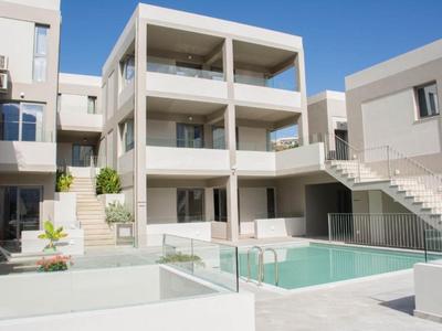Complesso alberghiero moderno con piscina e più balconi sotto un cielo azzurro limpido.