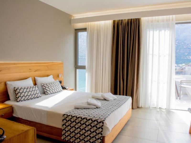 Hell und modern eingerichtetes Schlafzimmer mit großem Bett und Balkon mit Bergblick.