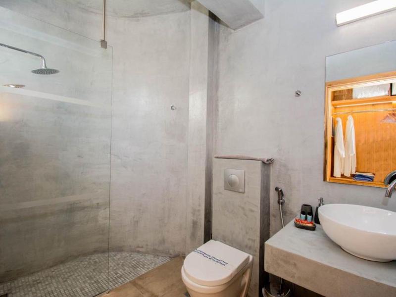 Modernes Badezimmer mit bodengleicher Dusche, weißer Toilette und rundem Waschbecken auf Betonplatte.