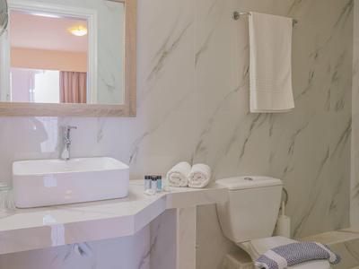 Helles Badezimmer mit weißem rechteckigem Waschbecken, Handtüchern und marmorierter Wandgestaltung.