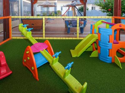 Bunter Kinderspielplatz mit Rutschen, Wippen und Klettergerüst auf grünem Kunstrasen.