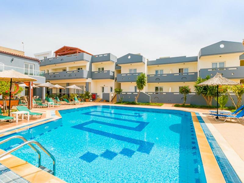 Großer blauer Pool mit Liegestühlen und modernen mehrstöckigen Gebäuden im Hintergrund.