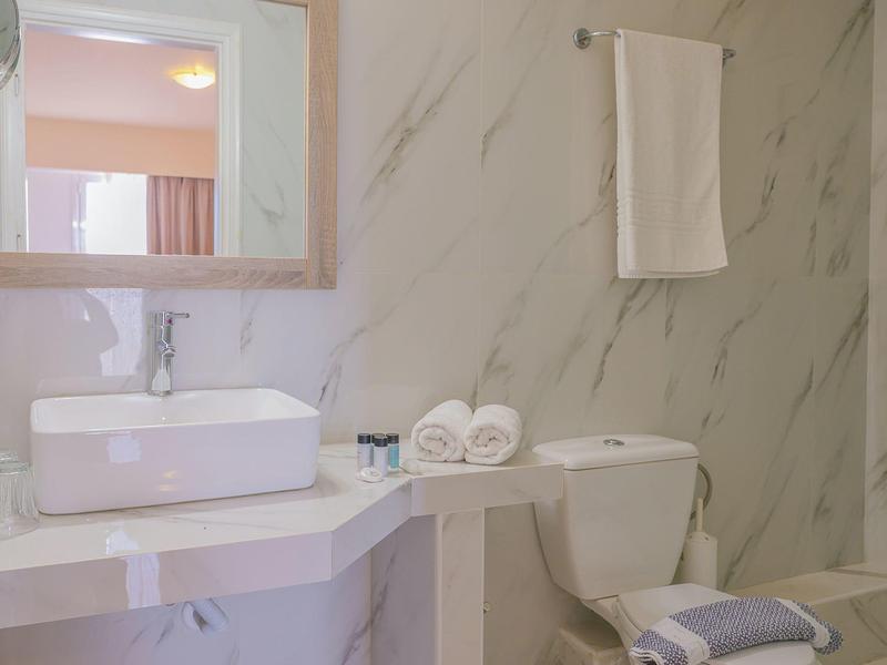 Helles Badezimmer mit weißem rechteckigem Waschbecken, Handtüchern und marmorierter Wandgestaltung.