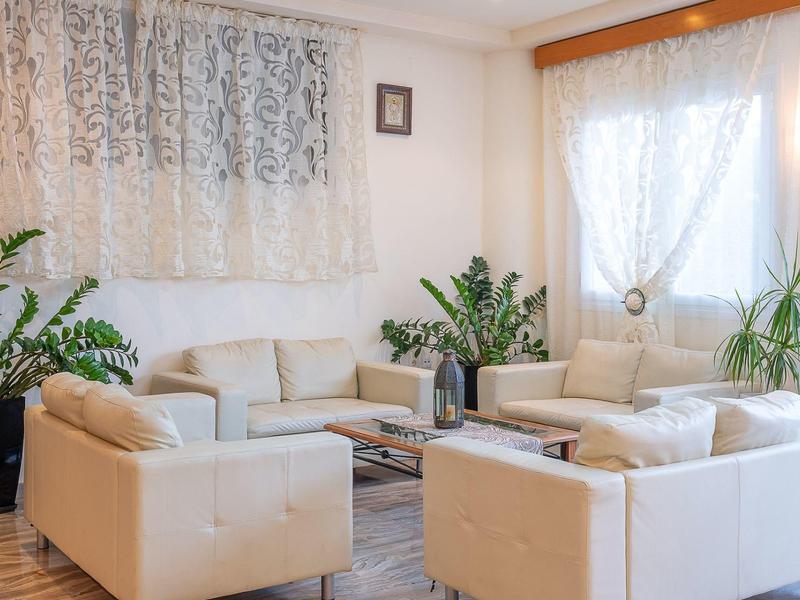 Helles Wohnzimmer mit weißen Sofas, großem Fenster, Pflanzen und Holzboden.