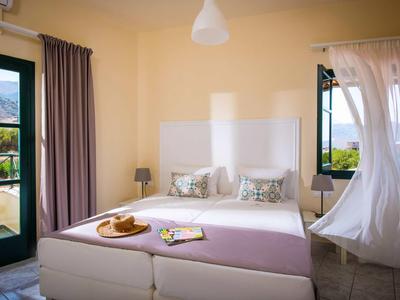 Jasna sypialnia z podwójnym łóżkiem, dużymi oknami i widokiem na przyrodę