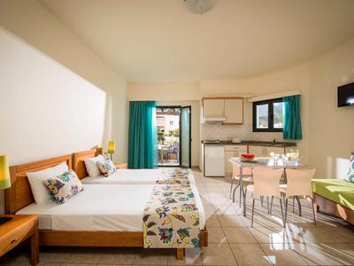 Jasny pokój hotelowy z łóżkiem podwójnym, aneksem kuchennym, przytulnym kącikiem wypoczynkowym i dostępem do balkonu lub tarasu.