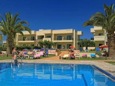 Basen hotelowy z leżakami, palmami i wielopiętrowym budynkiem pod czystym niebem