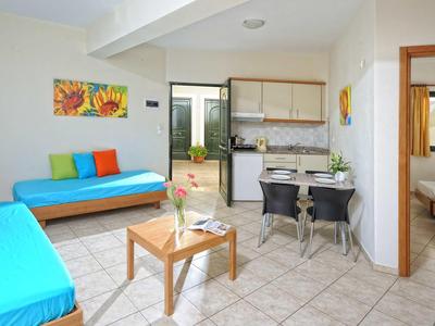 Jasne mieszkanie wakacyjne z dwoma niebieskimi sofami, stołem jadalnym i otwartą kuchnią.