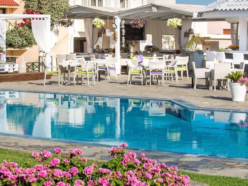 Moderner Außenbereich mit klarem Pool, blühenden Blumen und weißen Sitzmöbeln in hellem Ambiente.