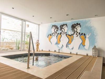 Área interior con jacuzzi y arte mural con figuras abstractas en un hotel