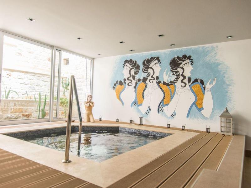 Moderner Innen-Schwimmbadbereich mit quadratischem Pool, Holzverkleidung und bunter Wandkunst.