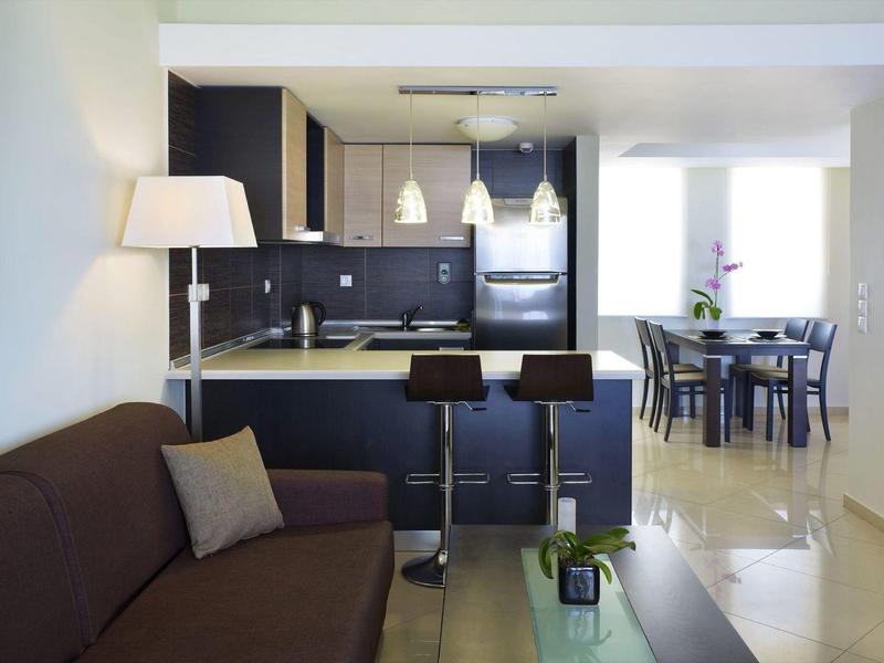 Moderne offene Küche mit schwarzer Einrichtung, Barhockern, brauem Sofa und Essbereich im Hintergrund.