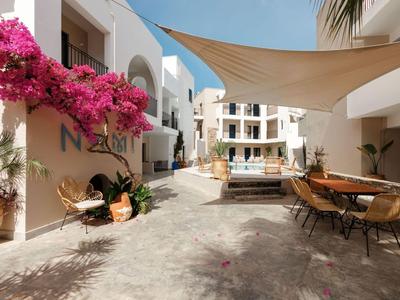 Dziedziniec z bielonymi budynkami, kwitnącą bugenwillią i miejscami do siedzenia pod żaglem przeciwsłonecznym