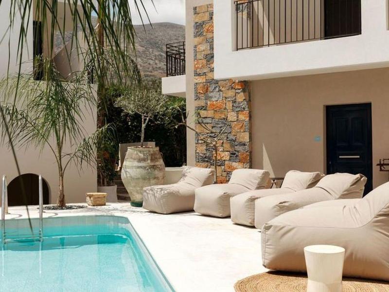 Modern pool area with comfortable bean bag chairs, plants, and stone wall accents.