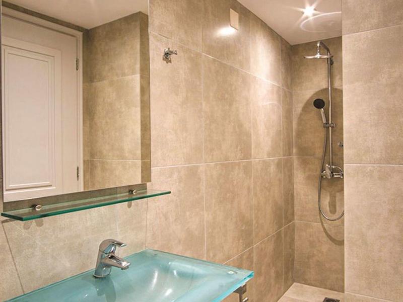 Modern bathroom with glass sink and walk-in shower in light natural tones.