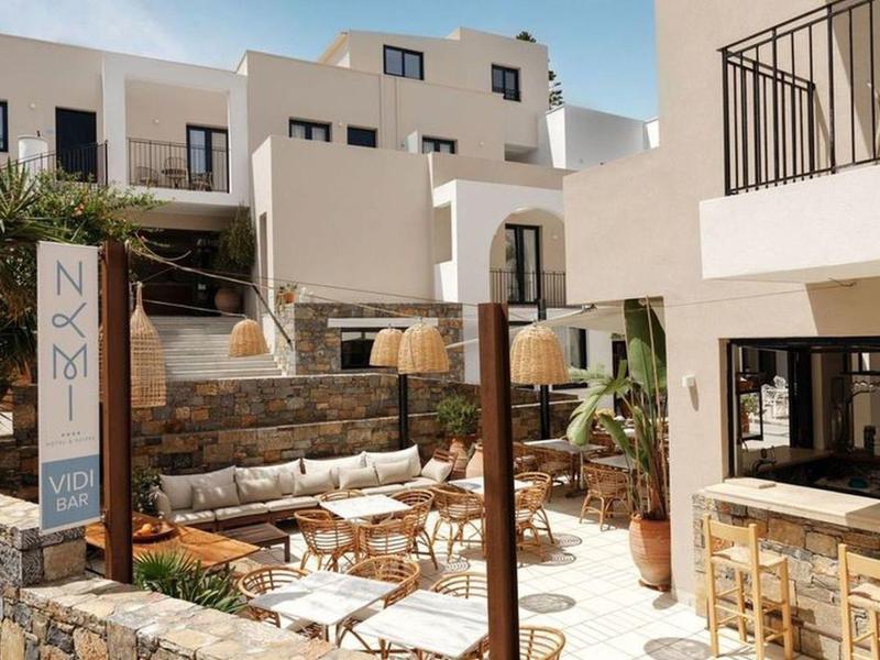 Cozy outdoor area of a hotel with seating, white buildings, and plants.