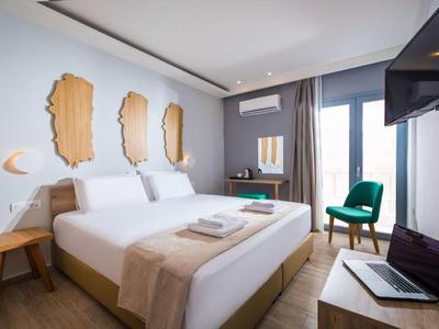 Modernes Hotelzimmer mit Doppelbett, hölzernen Wanddekorationen und Sitzbereich mit grünem Stuhl.