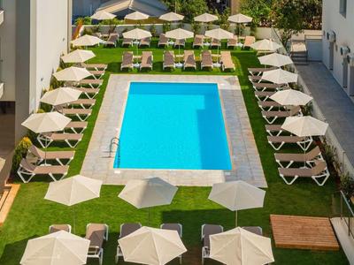 Rechteckiger Pool mit blauem Wasser, umgeben von Rasen, Liegestühlen und weißen Sonnenschirmen.
