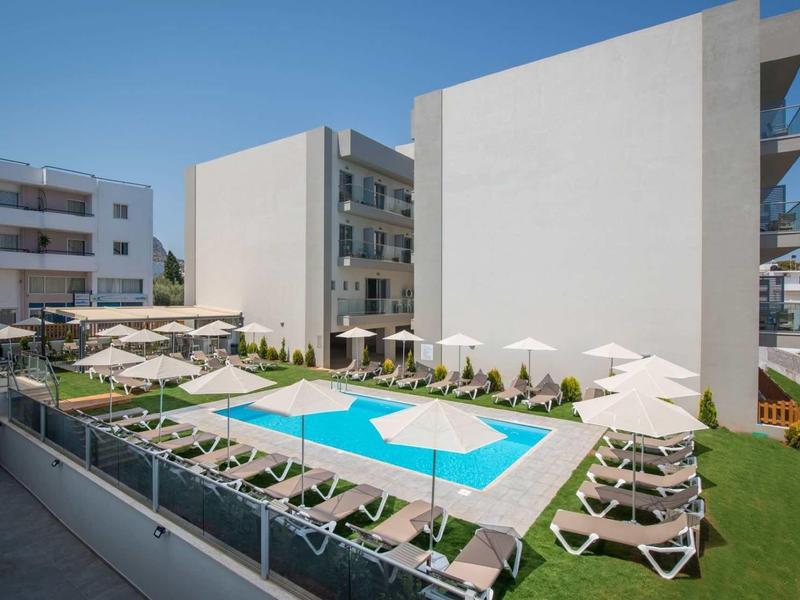 Moderne zwembadomgeving met ligbedden en parasols naast een hotelgebouw.