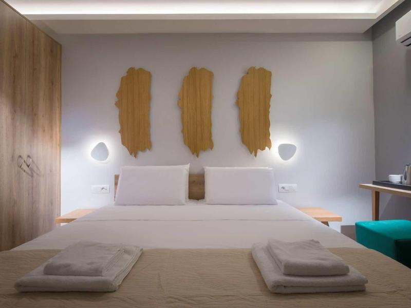 Modern hotelkamer met tweepersoonsbed, houten wandaccenten en gedimde verlichting.