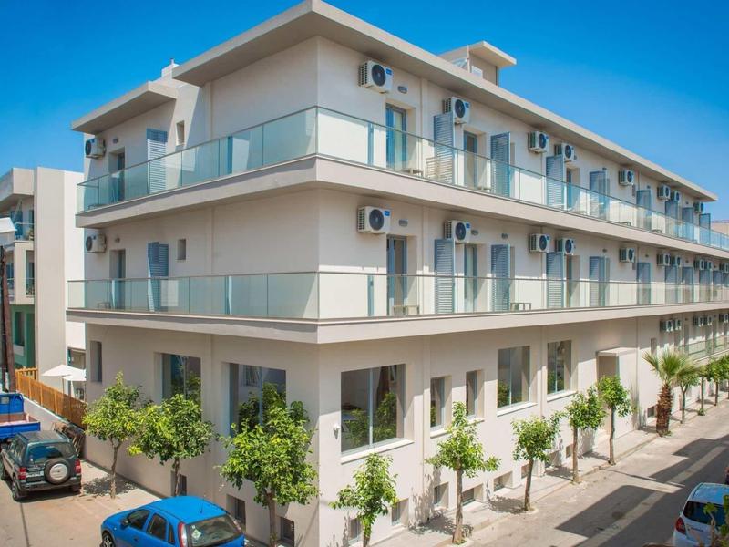 Modern hotelgebouw met drie verdiepingen, glazen balkons en airconditioning onder een heldere hemel.