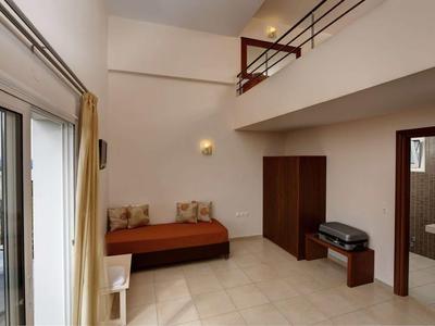 Una stanza arredata semplicemente con letto, armadio e accesso al balcone.