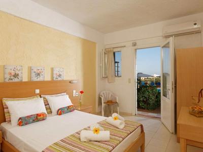 Camera d'hotel luminosa con letto matrimoniale, tavolo, sedia e balcone con vista sul cortile.