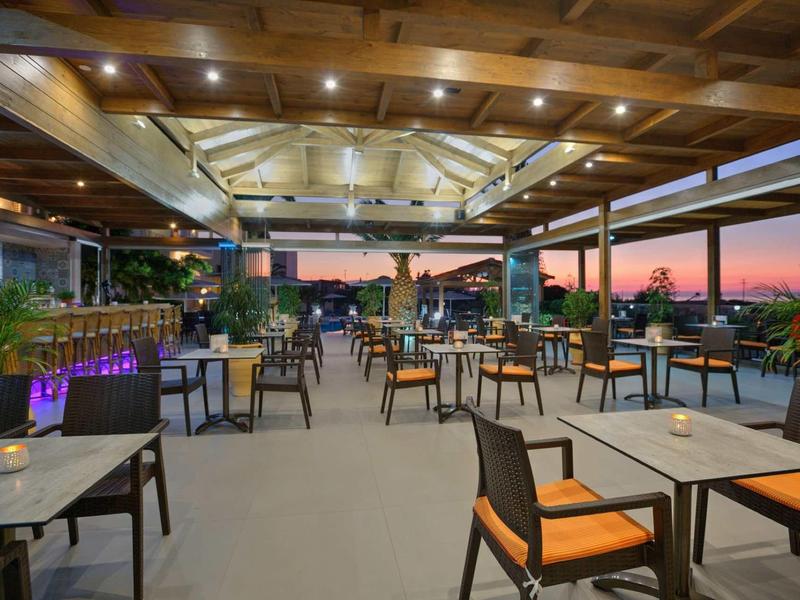 Espace terrasse d'hôtel ouvert avec tables et chaises au coucher du soleil.