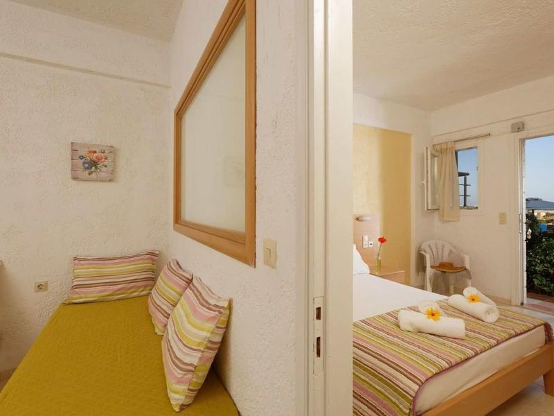 Deux chambres lumineuses séparées par un mur, avec lits, sièges et vue par la fenêtre.