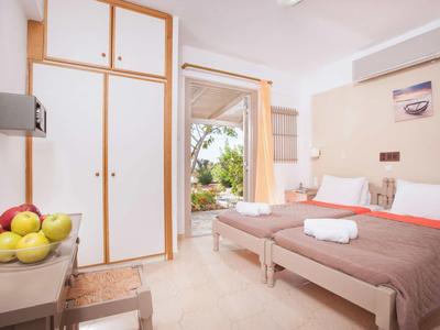 Camera d'hotel con due letti singoli, cesta di frutta e porta aperta sul giardino