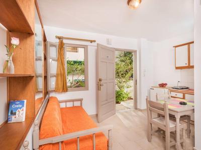 Soggiorno luminoso con divano arancione, tavolo da pranzo e porta aperta verso il giardino.