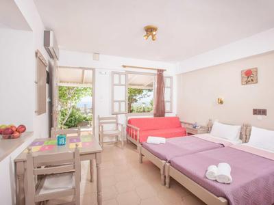 Camera d'hotel luminosa con due letti, tavolo e vista su una terrazza.