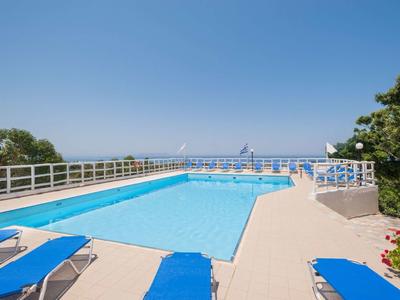 Ein rechteckiger Pool mit blauem Wasser, umgeben von blauen Liegestühlen und einem weißen Geländer.