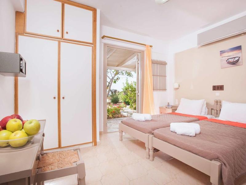 Chambre d'hôtel lumineuse avec deux lits simples et vue sur un balcon.