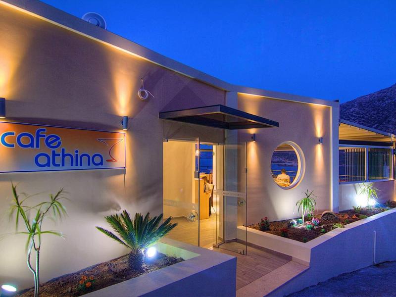 Modernes Café mit warmen Lichtern, Pflanzen und runden Fenstern bei Abenddämmerung.