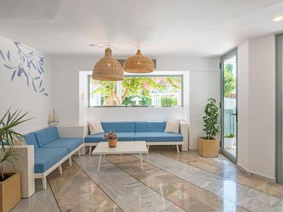 Lounge moderna e luminosa con divano ad angolo, tavolino e grandi finestre.