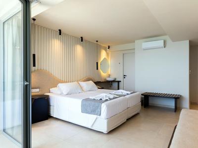 Chambre d'hôtel moderne avec grand lit double, éclairage mural et accès au balcon.